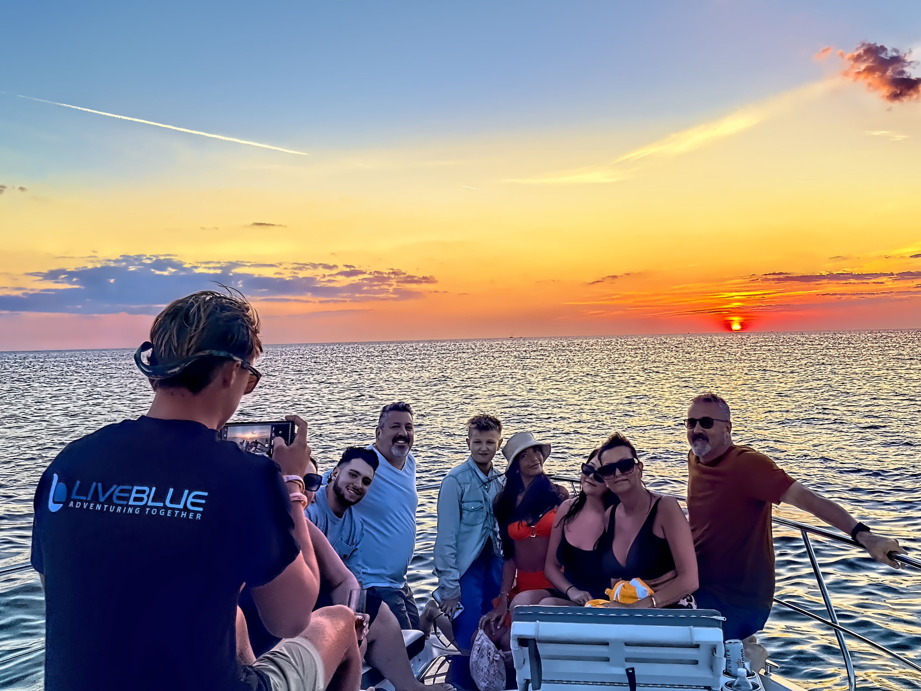 A group enjoying a stunning sunset cruise on a luxury yacht, captured by a LivBlue crew member, highlighting custom boat charters and island-hopping experiences.